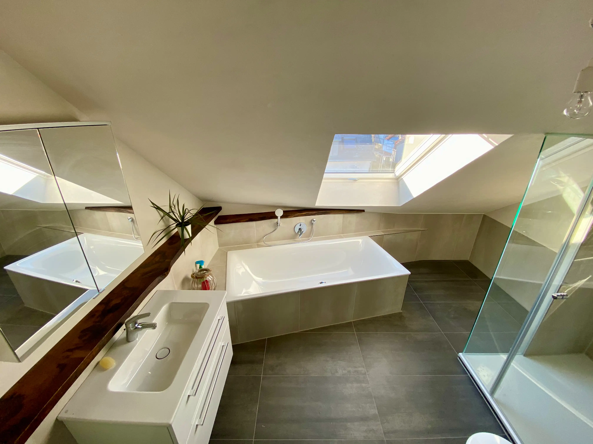 Wohlfühloase unterm Dach: Natürlicheㅤ Materialien und klares Design schaffen eine entspannte Atmosphäre im modernen Masterbad.